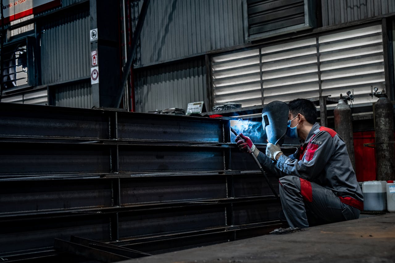 Skilled welder working diligently on metal structures inside a warehouse.