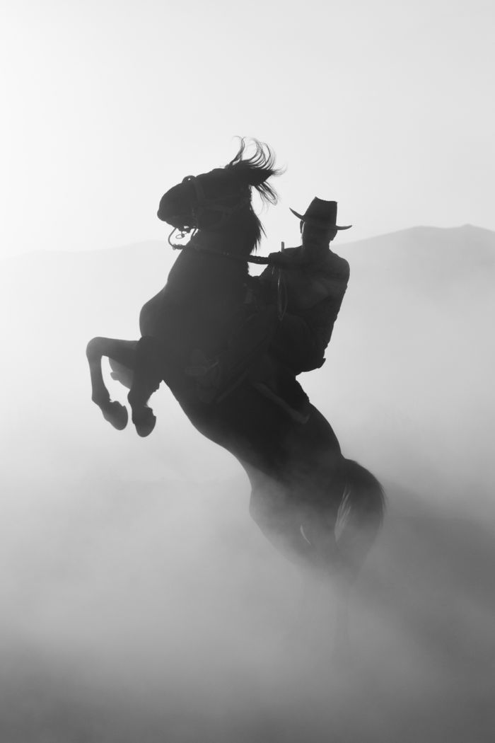 our-story Dramatic silhouette of a cowboy riding a rearing horse in a misty landscape of Kayseri, Turkey.