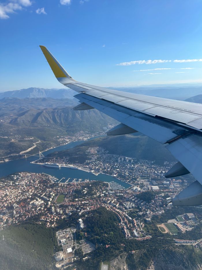 our-story Stunning aerial view of Dubrovnik, Croatia from an airplane window, showcasing city and coastline.