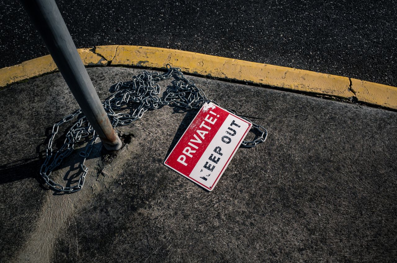 home-img A chained 'Private Keep Out' sign lies on an urban sidewalk, emphasizing security.